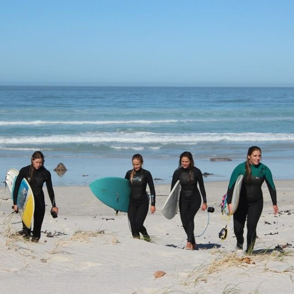 a group of people on a beach holding a surfboard