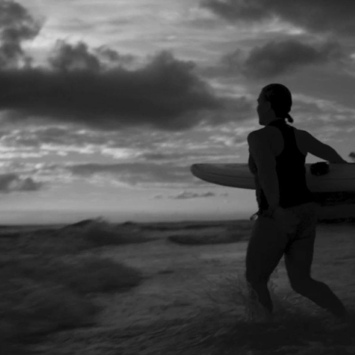 a man carrying a surf board walking on a beach