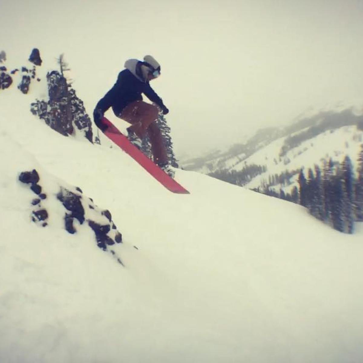 a man jumping in the air on a snow covered slope