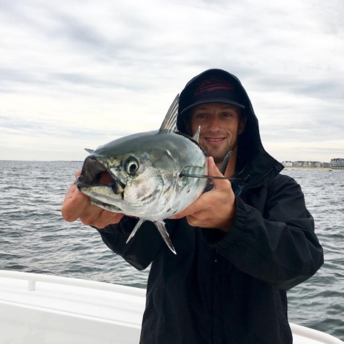 a man holding a fish on a boat in a body of water
