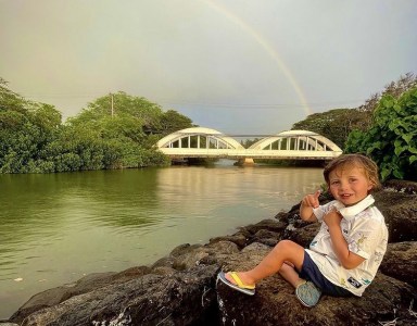 a young boy standing next to a body of water