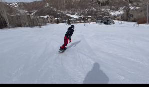 a man riding a snowboard down a snow covered slope