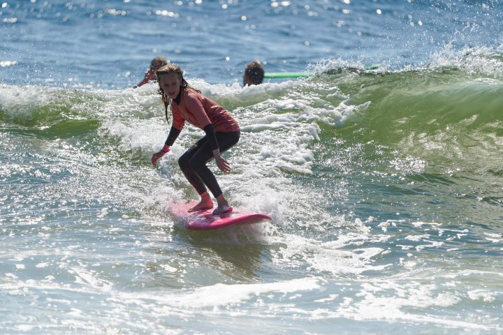 a young girl riding a wave on a surfboard in the ocean