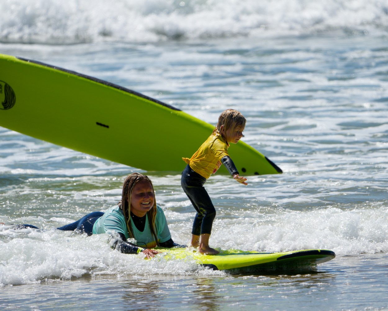 a young girl riding a wave on a surfboard in the water