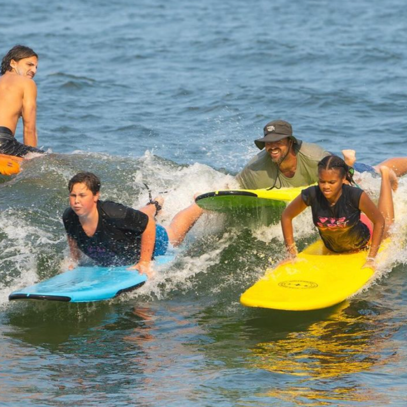 a small girl riding a wave on a surfboard in the water