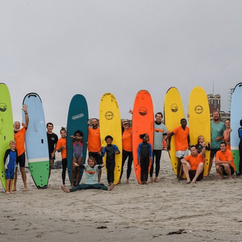 a group of people standing on a beach holding a surfboard