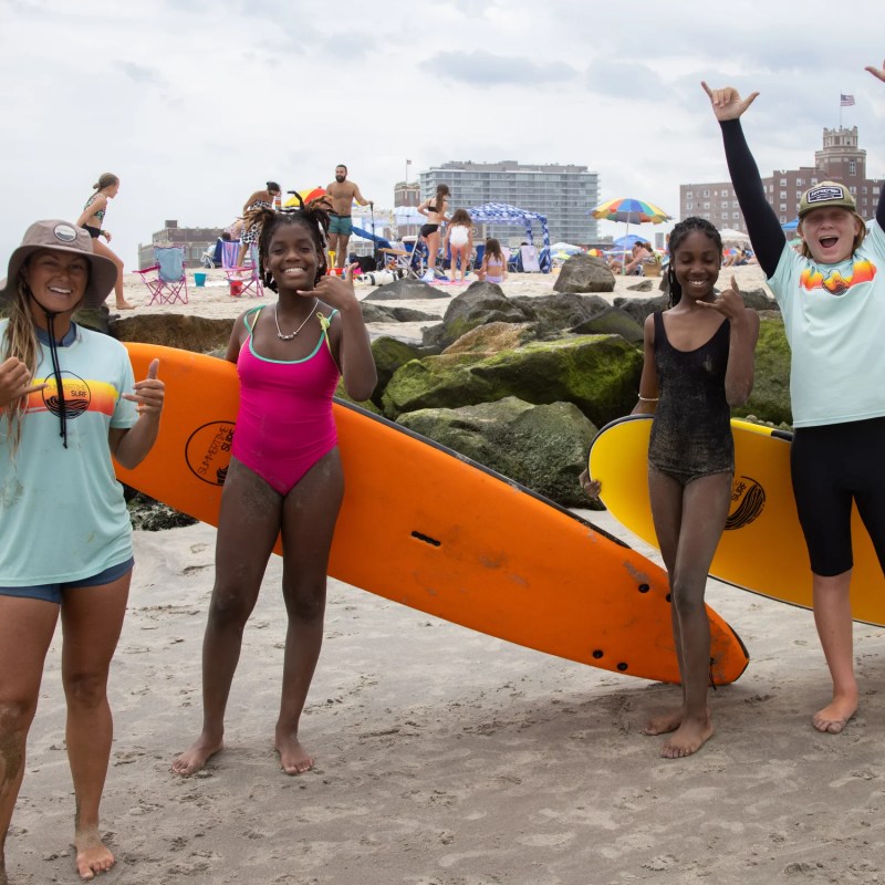 a woman standing on a beach holding a surfboard